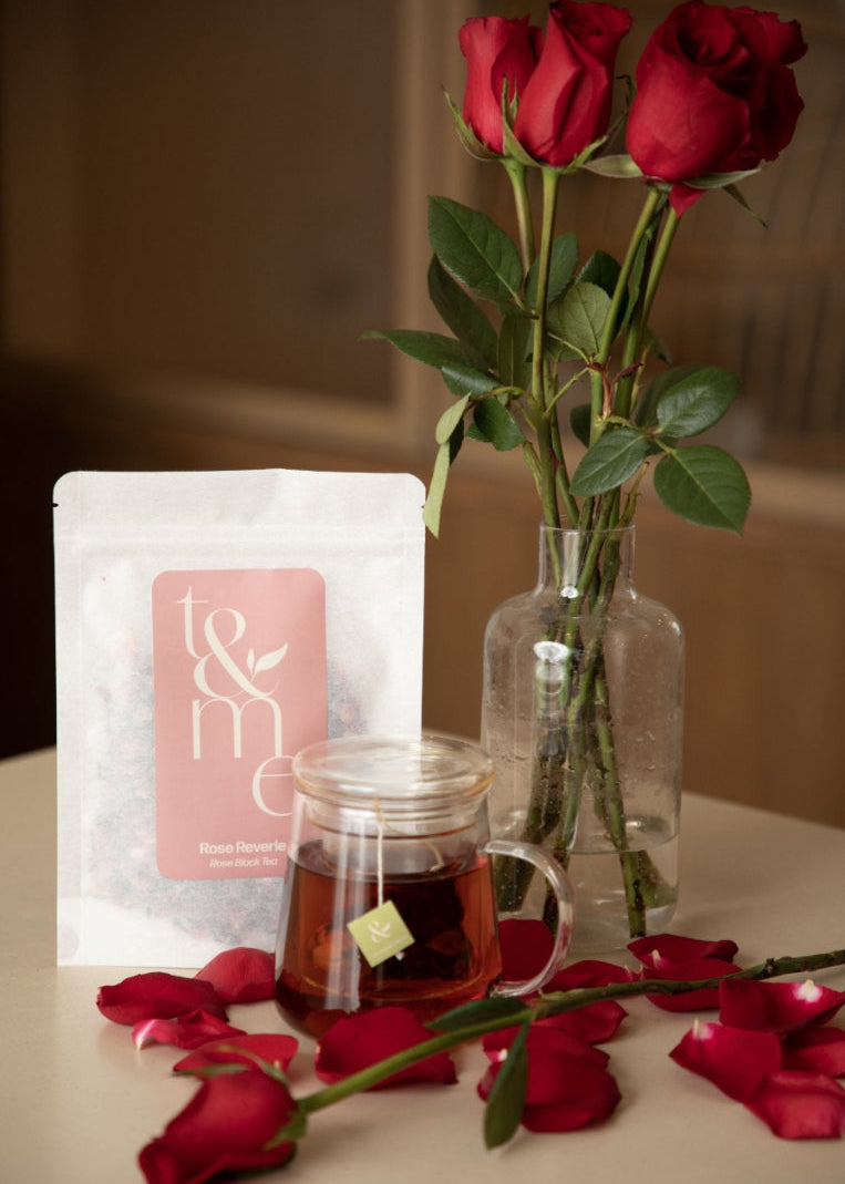 Tea bag, glass mug with tea, and red roses on a table