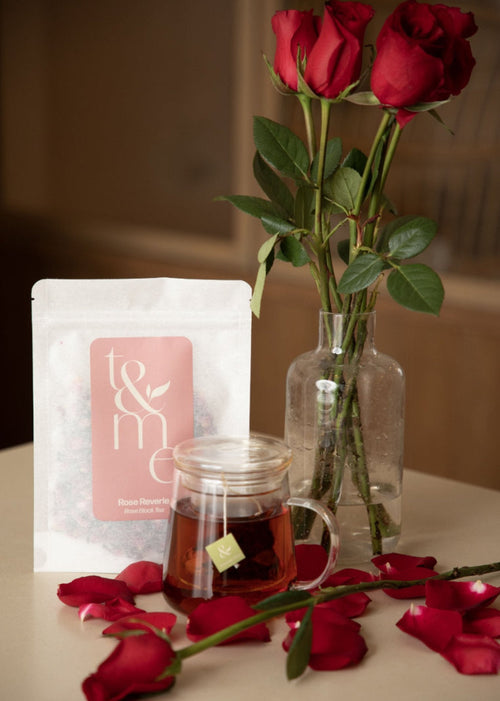 Tea bag, glass mug with tea, and red roses on a table
