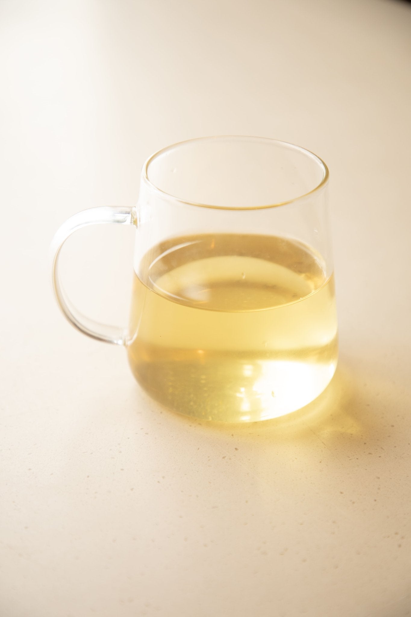 Clear glass mug with yellow liquid on a light background